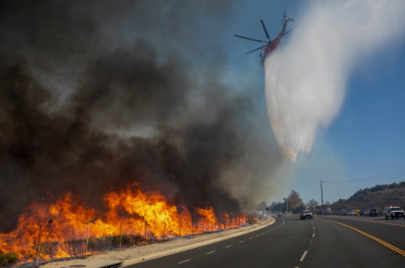 A firefighting helicopter makes a water drop over the Easy Fire in California.